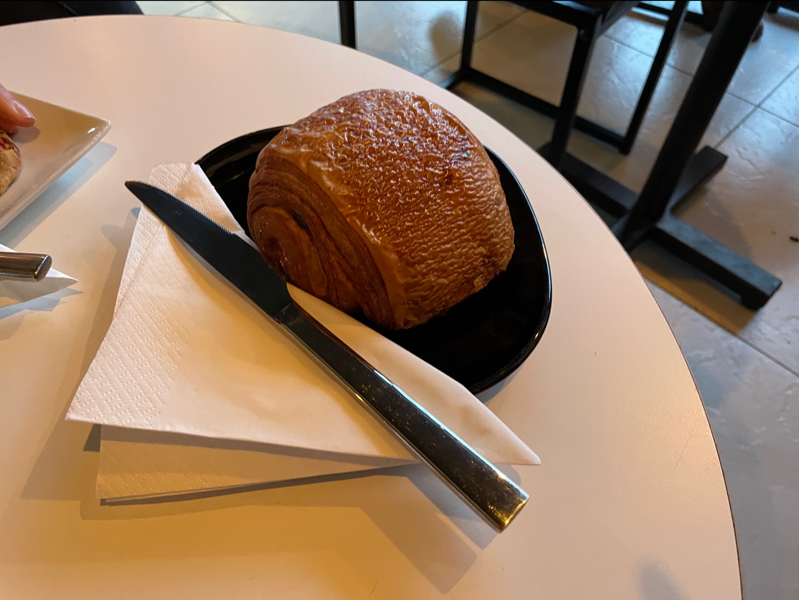 A pastry on a black plate at a café table